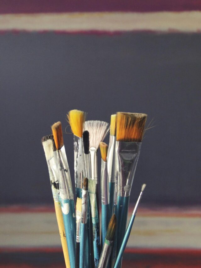 A set of paintbrushes in front of an abstract canvas, reflecting creativity and inspiration.